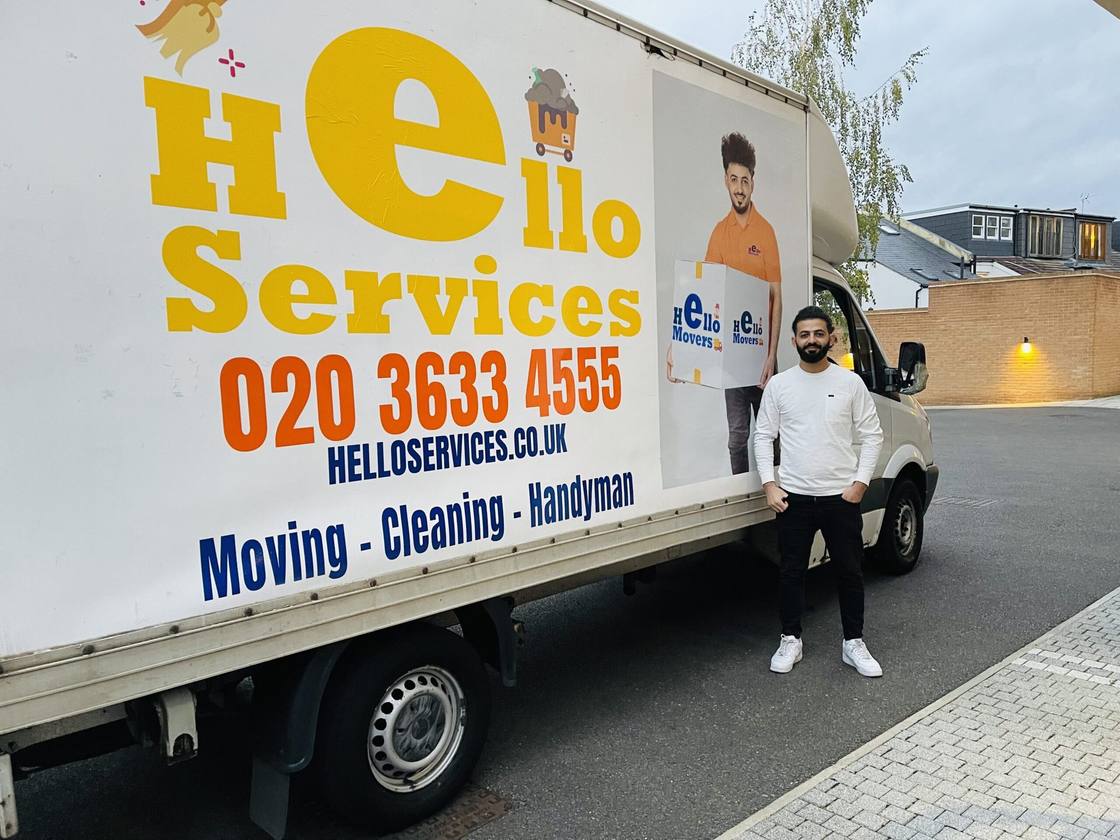 Hello Services mover lifting a shrink-wrapped item into the back of a loaded Hello Services van in Abram, Wigan