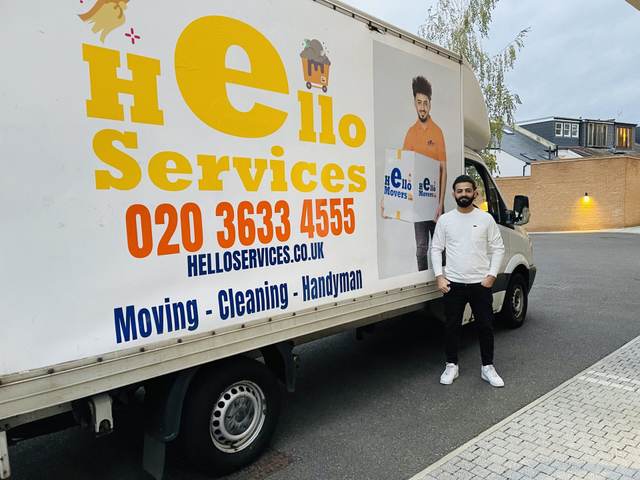 Hello Services mover lifting a shrink-wrapped item into the back of a loaded Hello Services van — Man with a van in Greater Manchester